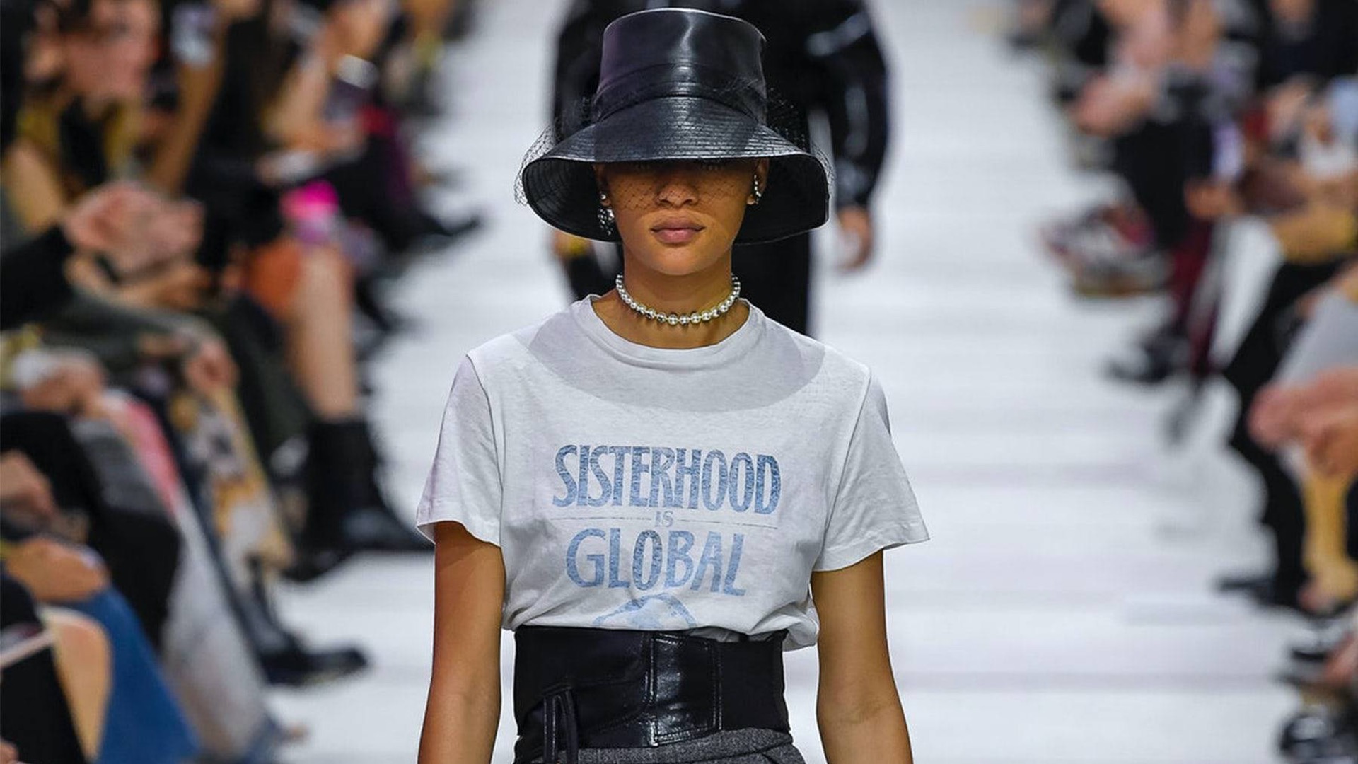 Une femme vêtue d'un t-shirt transmettant un message féministe marche dans un défilé de mode