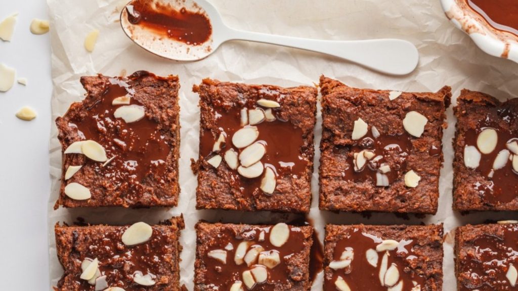 Dessert végane de brownies au chocolat séparés en portions égales sous forme de carrés sur un papier parchemin.