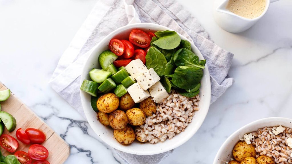Repas végane dans un bol contenant notamment des cubes de tofus, des patates et des légumes.